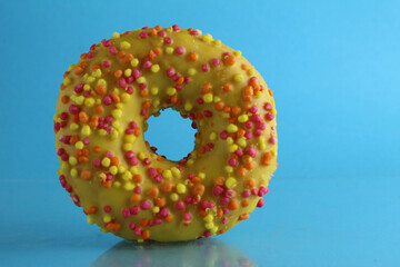 Berliner donut pink chocolate lies stands on a blue bright background with a place to text a copy of the still life for the kitchen breakfast sweet meal