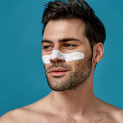 Closeup portrait of nice looking brunette guy with white mask applied on nose for cleansing pores...