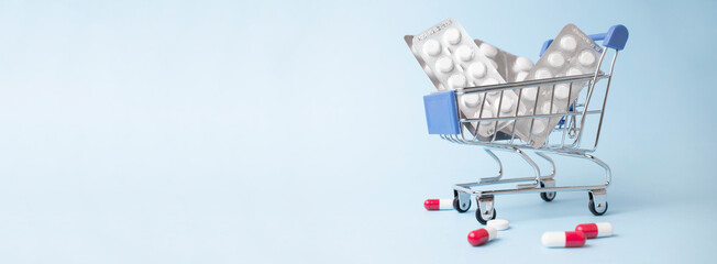 Medicine, vitamins and antioxidant supplements in trolley or shopping cart online on blue background