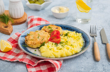 Homemade fish cakes or cutlets with mashed potatoes on a blue plate on a light concrete background. Fish recipes.