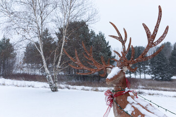 Deer figurine with holiday ribbon, standing in a snowy landscape in Maine.