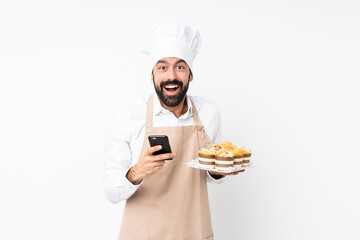 Young man holding muffin cake over isolated white background surprised and sending a message