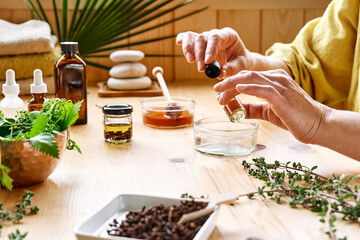 Woman prepares aromatherapy session at the table with essential oil diffuser medical herbs,...