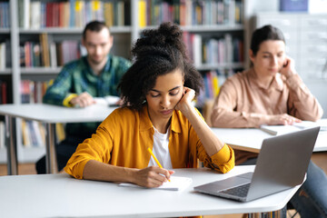 Students at lecture. Concentrated serious african american female student sitting at table in...