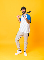 Full-length shot of man over isolated yellow background playing baseball and pointing to the front