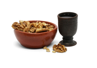 Clay bowl with walnuts and pine nuts and a ceramic glass with a drink (tincture, balm or other). Highlighted on a white background.