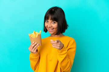 Young brunette woman holding fried chips over isolated blue background pointing front with happy expression