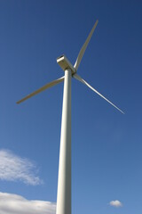 A Wind Turbine Creating Electricity from Wind Power using Induction with a Blue Sky in the Background
