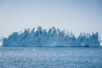 Bright sunny day in Antarctica. Full calm and reflection of icebergs in deep clear water. Travel by the ship among ices. Snow and ices of the Antarctic islands.