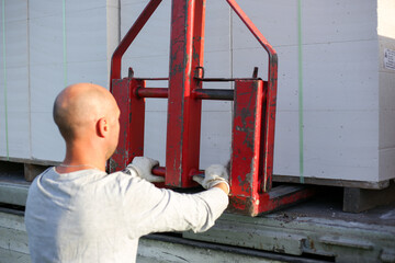 Unloading building blocks from a truck using a crane. Hydraulic manipulator.