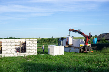 Fototapeta na wymiar Unloading building blocks from a truck using a crane. Hydraulic manipulator.