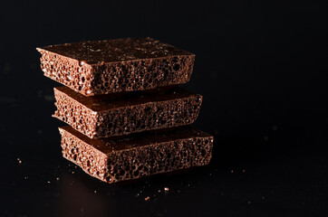 Pieces of delicious porous chocolate on a dark background