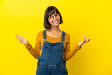 Young pregnant woman over isolated yellow background smiling a lot