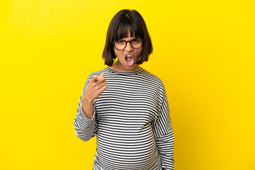 Young pregnant woman over isolated yellow background frustrated and pointing to the front