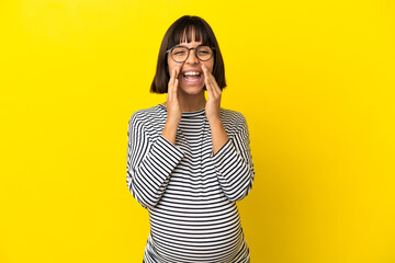 Young pregnant woman over isolated yellow background shouting and announcing something
