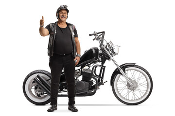 Obraz na płótnie Canvas Full length portrait of a mature biker with a custom chopper gesturing thumbs up