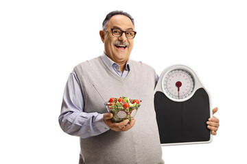 Happy mature man holding a healthy fresh salad in a bowl and a measuring scale