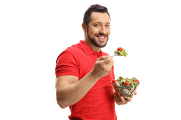 Smiling young man eating a healthy fresh salad in a bowl