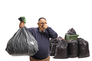 Mature man throwing a smelly waste bag in a bin