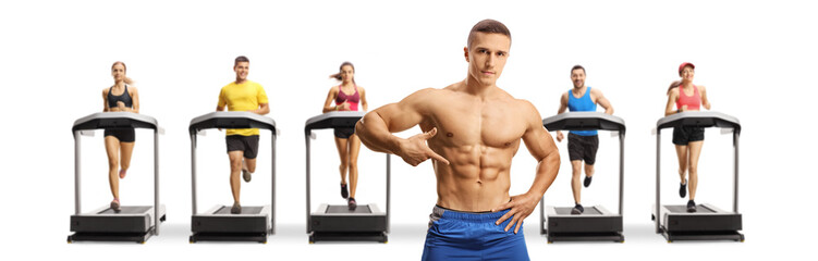 Obraz premium Topless muscular bodybuilder posing in front of people running on treadmills