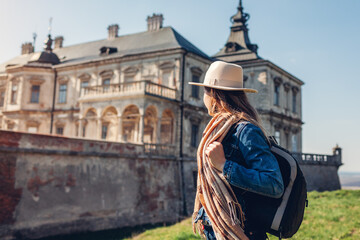 Fototapeta na wymiar Tourist woman enjoys view of castle in Pidhirtsi. Travel to historic places of interest and landmarks in Western Ukraine