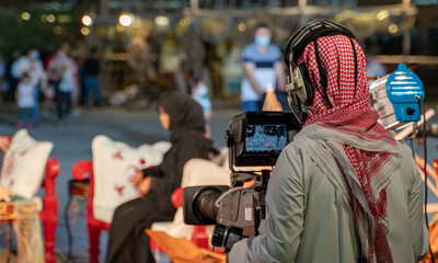 An Arab man recording a live interview video at an outdoor event in Qatar. Selective focus