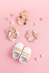 Baby shoes and teethers on pink background. Organic newborn fashion, branding, small business idea