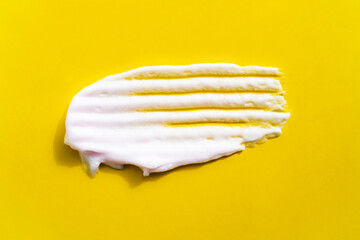 Textured smear of white creamy foam on illuminating yellow background. Face, body care beauty selfcare banner.