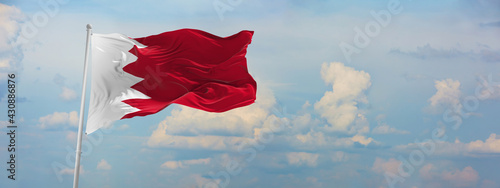 flag of Bahrain at cloudy sky background on sunset, panoramic view. Patriotic concept about Bahrain and copy space for wide banner. 3d illustration