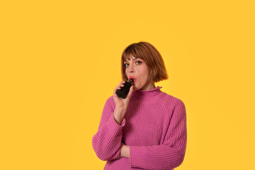 close up in front of a Yellow brackground of a sweetie girl with short Red hair, her sweater Is Pink. Shi Is smoking a elettronic sigarette