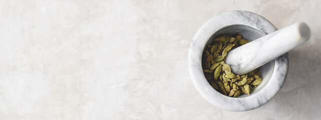 Cardamom pods in a marble mortar banner with copy space