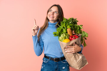 Young Lithuanian woman holding a grocery shopping bag pointing up a great idea