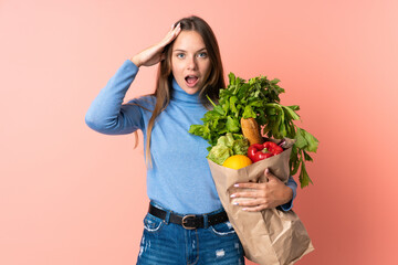 Young Lithuanian woman holding a grocery shopping bag with surprise expression