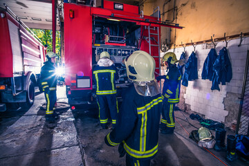 Obraz na płótnie Canvas Group of firefighters preparing and inspecting pressure and water in the fire truck inside the fire station