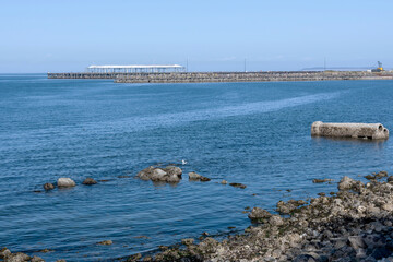 Rocky shoreline, blue water, and old pier
