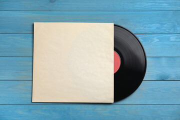 Vintage vinyl record with paper cover on blue wooden background, top view