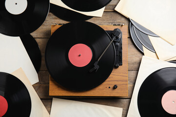 Modern player and vinyl records on wooden background, flat lay