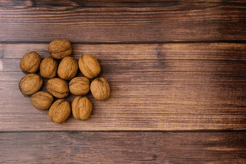 Bunch of walnuts lies on a wood background. Background with place for inscription.