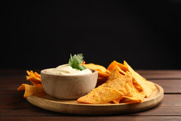 Delicious hummus with nachos on wooden table