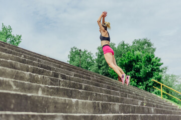 Fit healthy athlete, beautiful woman in tight sportswear jumping on stairs, warming up before jogging while looking highly motivated..