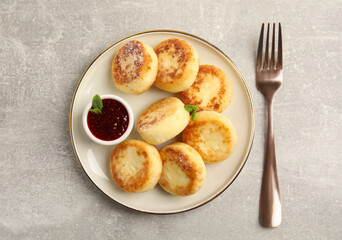 Delicious cottage cheese pancakes with jam and icing sugar on light grey table, flat lay
