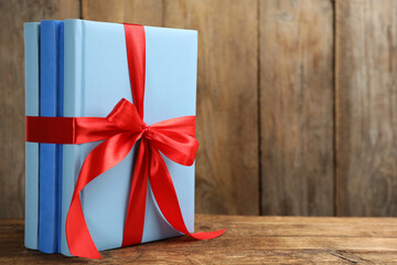Fototapeta premium Different books tied with red ribbon on wooden table, space for text