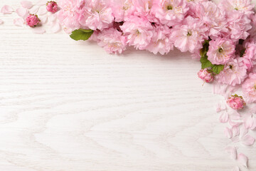 Beautiful sakura tree blossoms on white wooden background, flat lay. Space for text