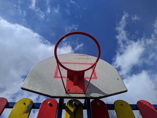 old basketball hoop against a background of blue sky and clouds