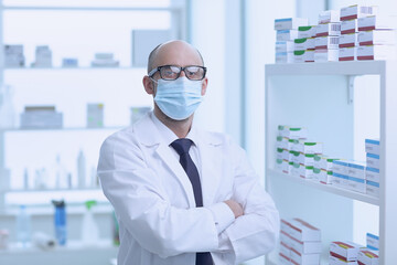 Pharmacist is Working in protective mask. Man Wearing Special Medical Uniform. Located in Pharmacy.