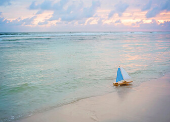 toy boat on gulf shore at sunset