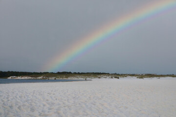 rainbow over white sand at the beach