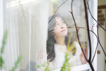 外の天気を確認する若い女性