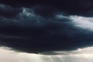 Black clouds with sun rays . Stormy weather with cloudburst