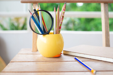 Colorful group of pencil with notebook on wood table.
